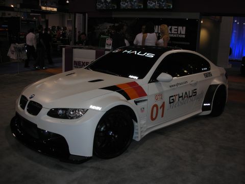 1998 Ford Crown Victoria - Modified BMW M3 with racing decals and widebody kit displayed indoors.