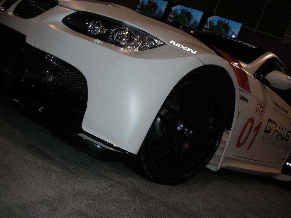 White BMW M3 GT2 race car with black accents and red stripes, showing the front wheel and fender. Text on the side reads 'GT2' and '01'