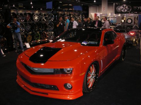 1998 Ford Crown Victoria - A bright orange sports car with a black stripe on the hood is displayed at an indoor event.
