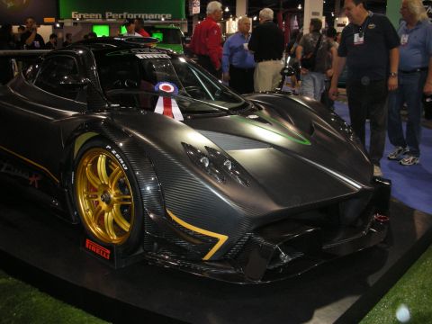 1998 Ford Crown Victoria - A dark Pagani Zonda R is displayed indoors with people in the background.