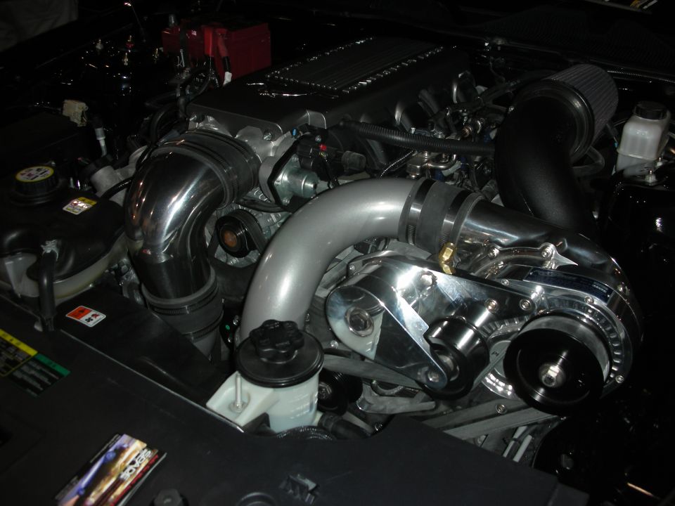 Engine bay with polished supercharger, chrome intake piping, and black air filter