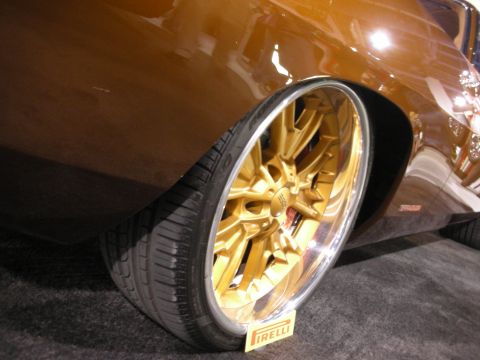1998 Ford Crown Victoria - A close-up shot focuses on a custom gold wheel with a Pirelli tire on a brown vehicle.