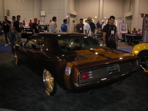 1998 Ford Crown Victoria - A customized muscle car with a distinctive brown and gold paint scheme is displayed indoors, gold wheels and a 'FOOSE' license plate.