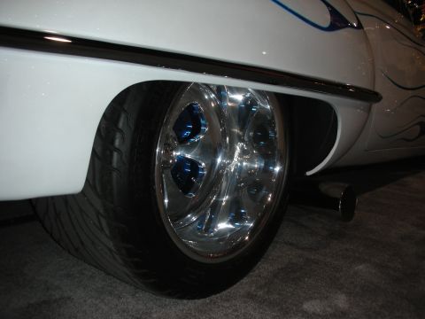 1998 Ford Crown Victoria - Customized car rear wheel and fender detail with chrome rims and blue flame graphics.