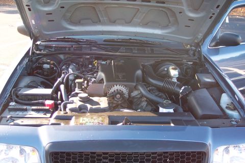 2001 Ford Crown Victoria - The engine bay of a 2001 Ford Crown Victoria is visible with the hood open, revealing the engine and various components.