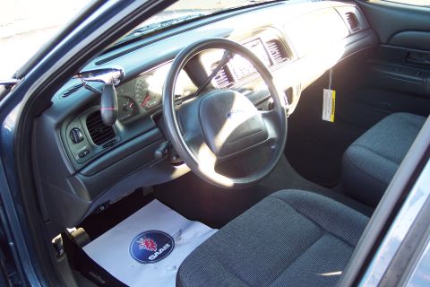 2001 Ford Crown Victoria - The interior of a car shows the steering wheel, dashboard gauges, and seats, with a Saab logo on a floor mat.