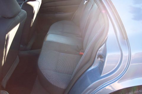 2001 Ford Crown Victoria - Interior view of the rear seats and door frame of a blue sedan.