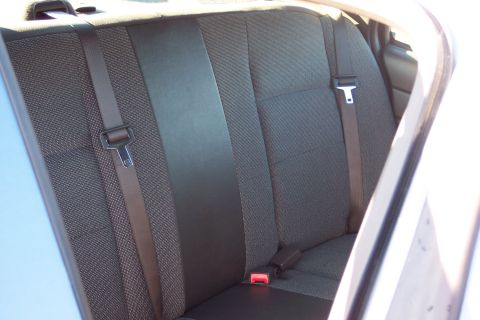 2001 Ford Crown Victoria - The interior of a car shows the back seat with visible seat belts and dark upholstery.