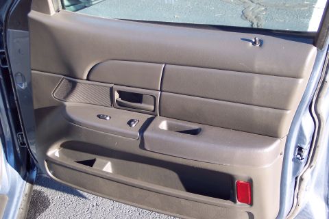 2001 Ford Crown Victoria - The interior door panel of a 2001 Ford Crown Victoria features power window controls and a storage compartment.