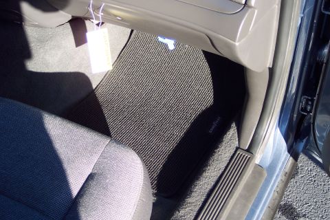 2001 Ford Crown Victoria - Car interior showing black ribbed floor mats and a gray fabric seat.