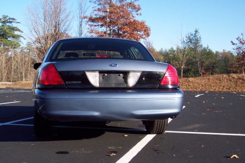 2001 Ford Crown Victoria - Rear view of a blue 2001 Ford Crown Victoria parked in a lot with autumn trees in the background.