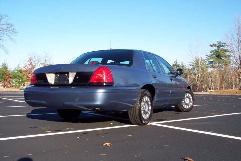 2001 Ford Crown Victoria - Rear view of a blue 2001 Ford Crown Victoria parked in an empty lot on a clear day.