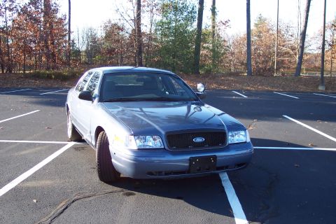 2001 Ford Crown Victoria - A blue 2001 Ford Crown Victoria is parked in an empty lot on a sunny day.