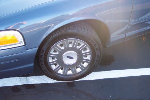 2001 Ford Crown Victoria - Close-up of the front passenger side wheel and fender of a blue Ford Crown Victoria.