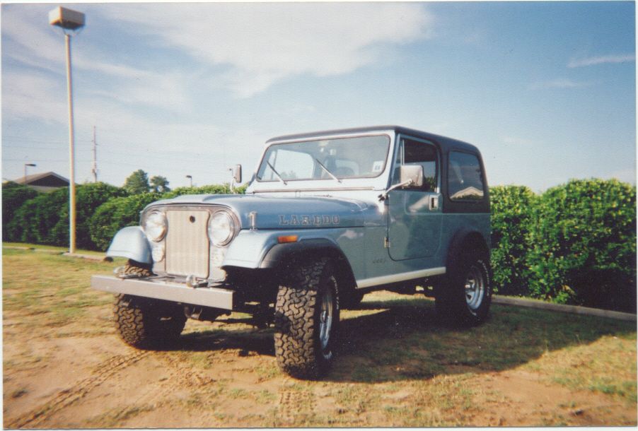 Blue Jeep CJ-7 with black hardtop, aftermarket wheels, and chrome grille