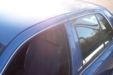 2001 Ford Crown Victoria - View of the interior seat and window of a blue sedan, with bright sunlight reflecting off the exterior.