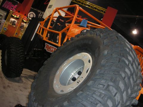 1998 Ford Crown Victoria - An orange off-road buggy with massive tires and a prominent roll cage is displayed indoors.
