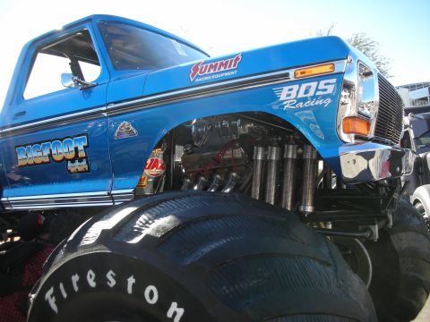 1998 Ford Crown Victoria - Close-up of a blue Bigfoot monster truck, highlighting its custom racing decals and massive tires.