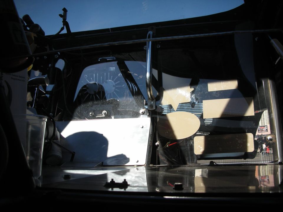 Interior view of a vehicle with a chrome grab handle and a fan visible through the windshield