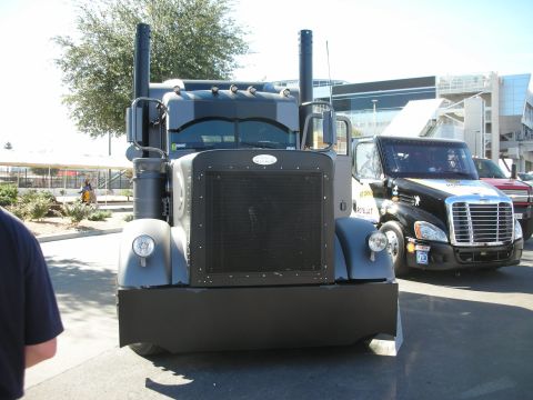 1998 Ford Crown Victoria - Two semi-trucks are parked side-by-side, one custom grey and the other black with decals.