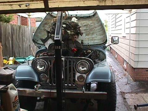 1984 Jeep Wrangler - A blue Jeep CJ-7 is parked in a garage with its hood open, revealing the engine bay.