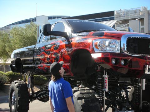 1998 Ford Crown Victoria - A heavily modified pickup truck with flame graphics and an extreme lift kit is shown from a low angle.