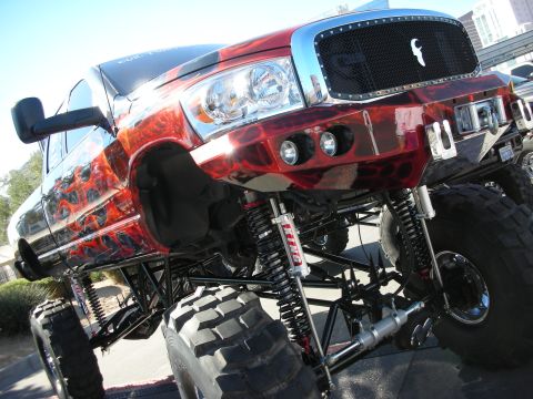 1998 Ford Crown Victoria - Custom lifted pickup truck with flame graphics and extreme suspension modifications.