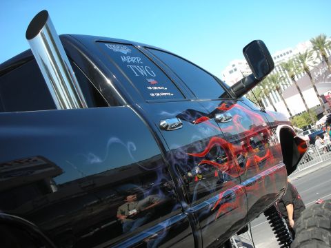 1998 Ford Crown Victoria - A customized black pickup truck with flame graphics and a tall exhaust stack is displayed outdoors.
