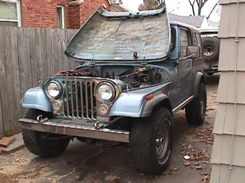 1984 Jeep Wrangler - A blue Jeep CJ is parked outside with its hood open, revealing the engine compartment.