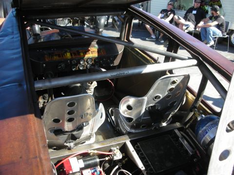1998 Ford Crown Victoria - The interior of a modified vehicle features racing bucket seats, a prominent roll cage, and a custom dashboard with multiple gauges.