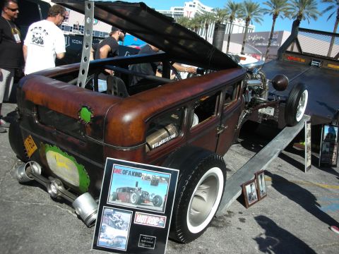 1998 Ford Crown Victoria - A custom-built rat rod hot rod is displayed on a ramp, its unique design and exposed engine components.