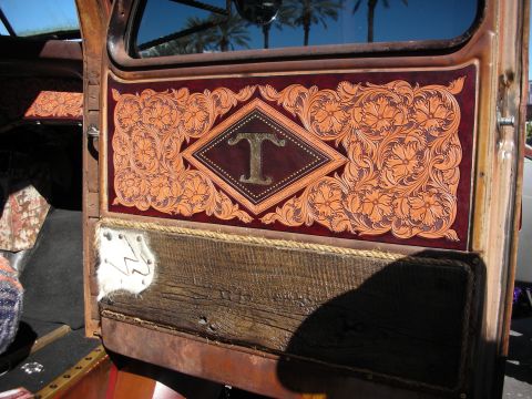 1998 Ford Crown Victoria - Close-up of a custom vehicle interior door panel with intricate leather tooling and a rustic wooden accent.