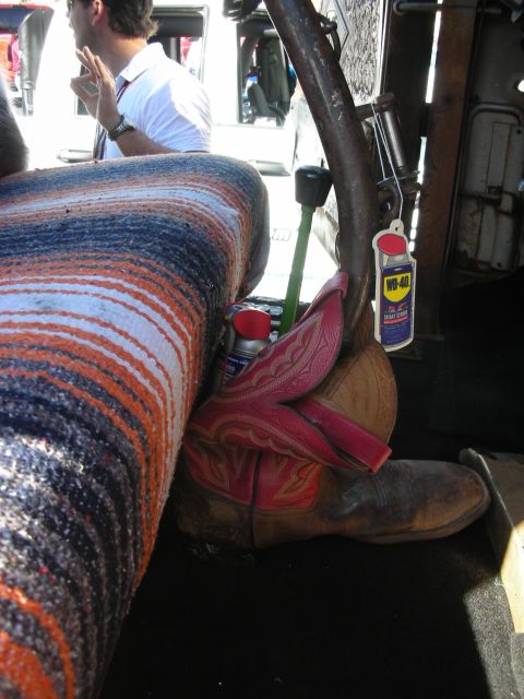 1998 Ford Crown Victoria - A pair of cowboy boots rests on the floor of a vehicle, accompanied by a WD-40 air freshener and a striped blanket.