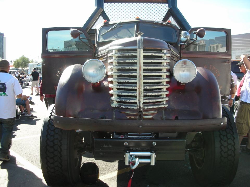 Front view of a large, old, maroon truck with a prominent chrome grille and large tires. Doors are open