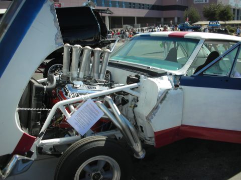 1998 Ford Crown Victoria - A custom race car is displayed with its hood open, revealing a powerful V8 engine and prominent intake stacks.