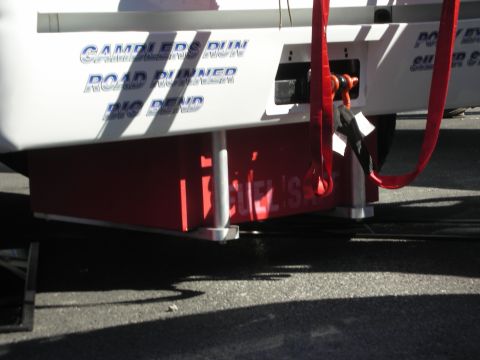 1998 Ford Crown Victoria - A trailer side shows text and red straps, with a red fuel tank visible below.