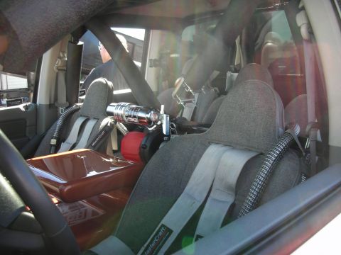 1998 Ford Crown Victoria - The interior of a modified vehicle shows racing seats, a roll cage, and a chrome fire extinguisher mounted between the seats.