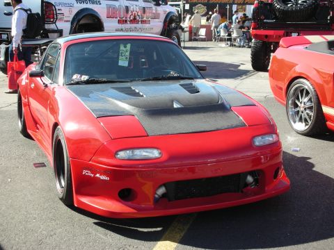 1998 Ford Crown Victoria - A red sports car with a carbon fiber hood and custom body kit is parked outdoors.