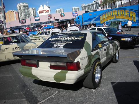 1998 Ford Crown Victoria - A camouflaged Ford Mustang with racing slicks and a spoiler is parked outdoors.