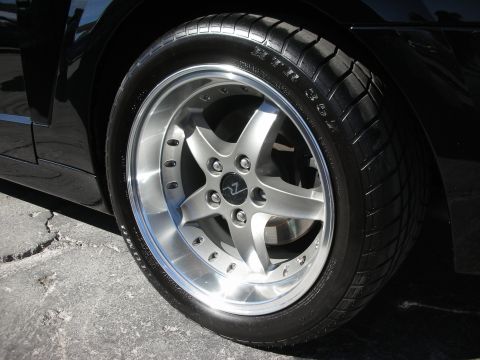 1998 Ford Crown Victoria - Close-up of a black car's wheel a custom silver five-spoke rim and performance tire.