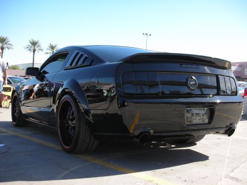 1998 Ford Crown Victoria - Rear view of a black Ford Mustang GT with tinted taillights and a custom spoiler.