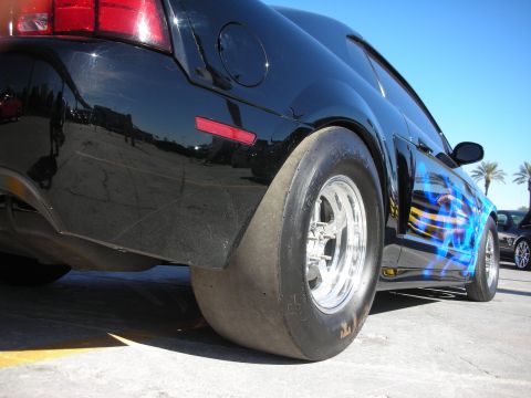 1998 Ford Crown Victoria - A black car with custom blue flame graphics and drag racing tires is shown from the rear quarter angle.