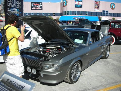 1998 Ford Crown Victoria - A gray 1967 Ford Mustang is displayed with its hood open, revealing the engine, next to a sign identifying it.