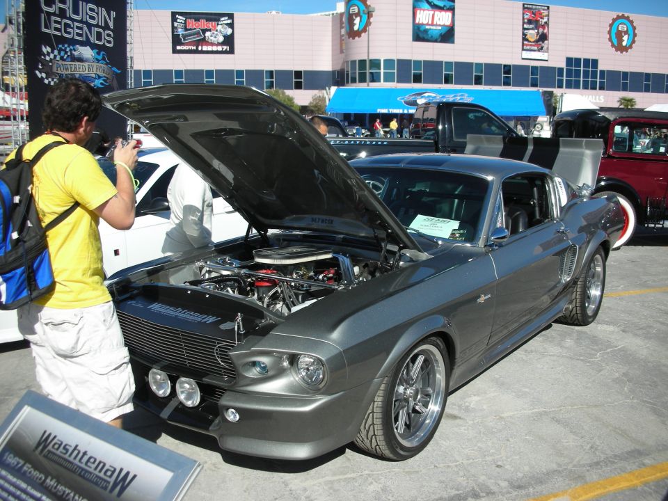 Gray 1967 Ford Mustang with hood open, custom wheels, and a sign in front