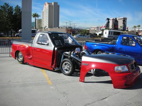 1998 Ford Crown Victoria - A customized red and silver pickup truck, possibly a 1998 Ford F-150, is shown with its engine exposed and front clip detached, parked next…