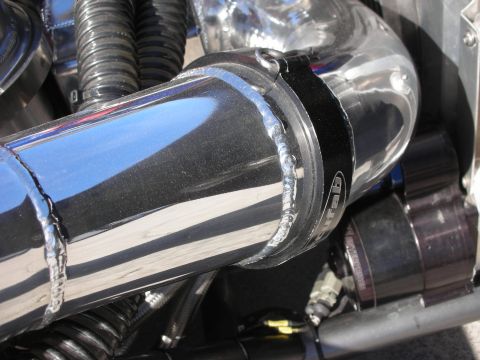 1998 Ford Crown Victoria - Close-up of a chrome intake pipe with visible welds and a black clamp, possibly from a custom engine build.