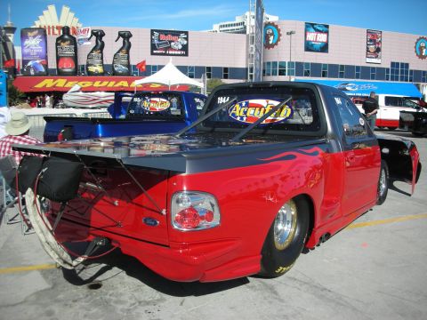 1998 Ford Crown Victoria - A customized red and grey pickup truck with flame decals and racing slicks is parked at an outdoor event.