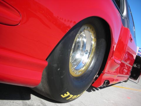 1998 Ford Crown Victoria - Rear wheel and fender of a modified red vehicle, possibly a drag car.