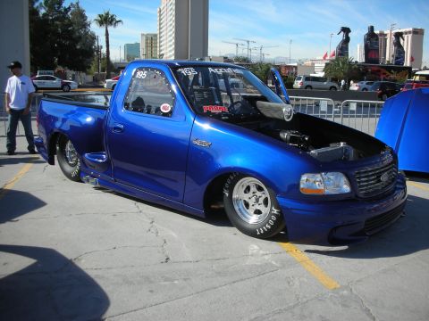 1998 Ford Crown Victoria - This modified 1998 Ford F-150 Lightning drag truck features a custom blue paint job, racing slicks, and an exposed engine compartment.