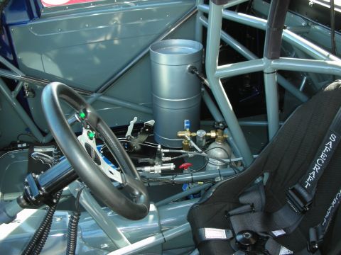 1998 Ford Crown Victoria - The interior of a race car shows a roll cage, racing seat, steering wheel, and a nitrous oxide tank.